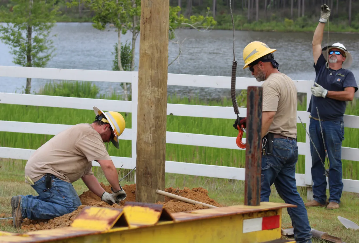 Heavy machinery crew stabilizing power line post