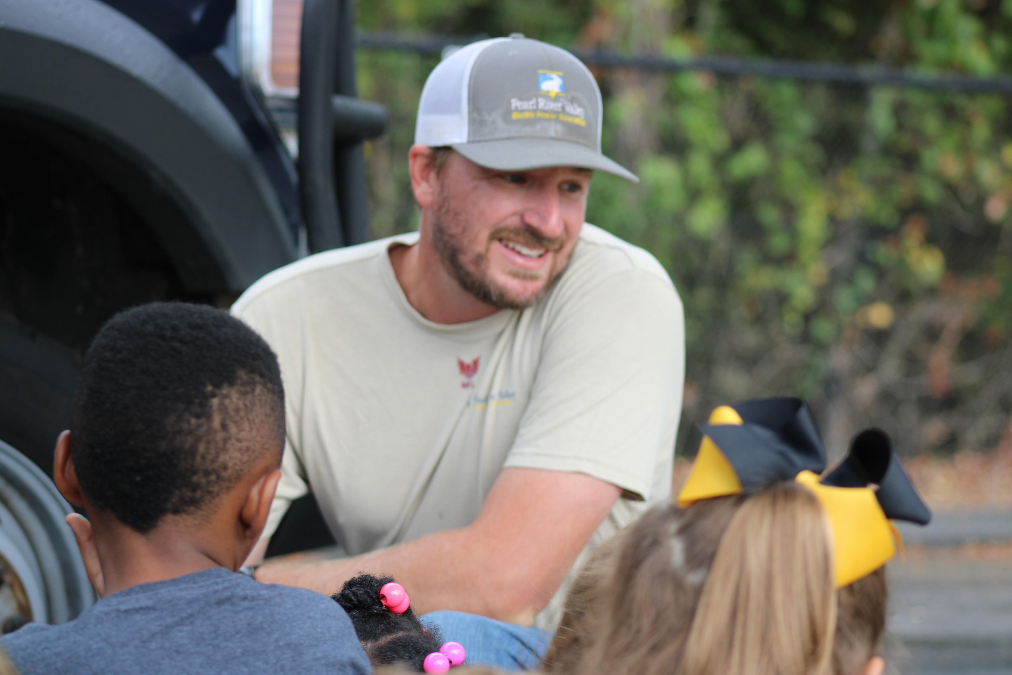 Caucasian male helping grade school kids learn something about electrical work