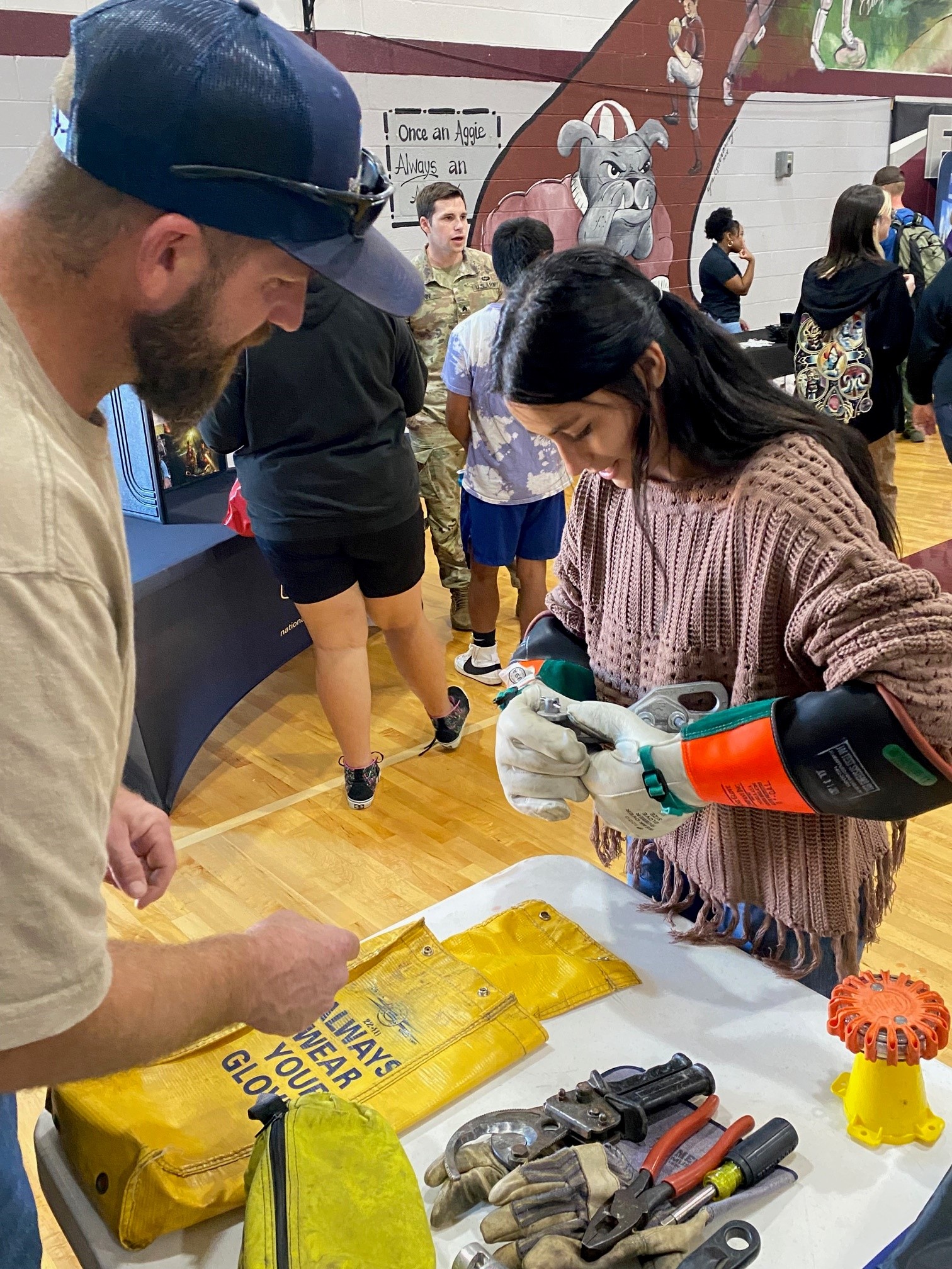Young woman trying on electrical gloves at a school function or job fair