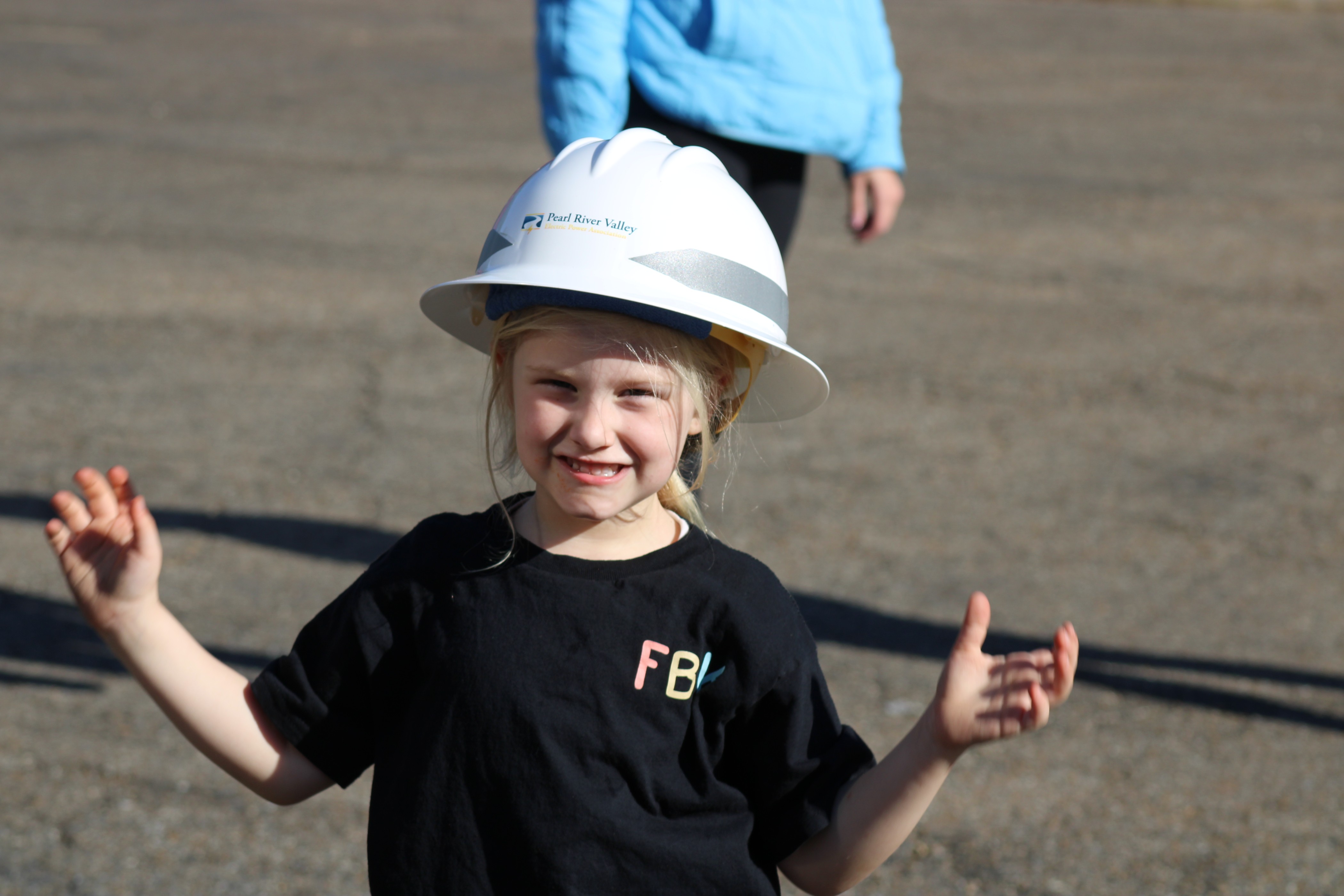 Grade school girl posing in a Pearl River Valley hard hat to showcase safety at a school event