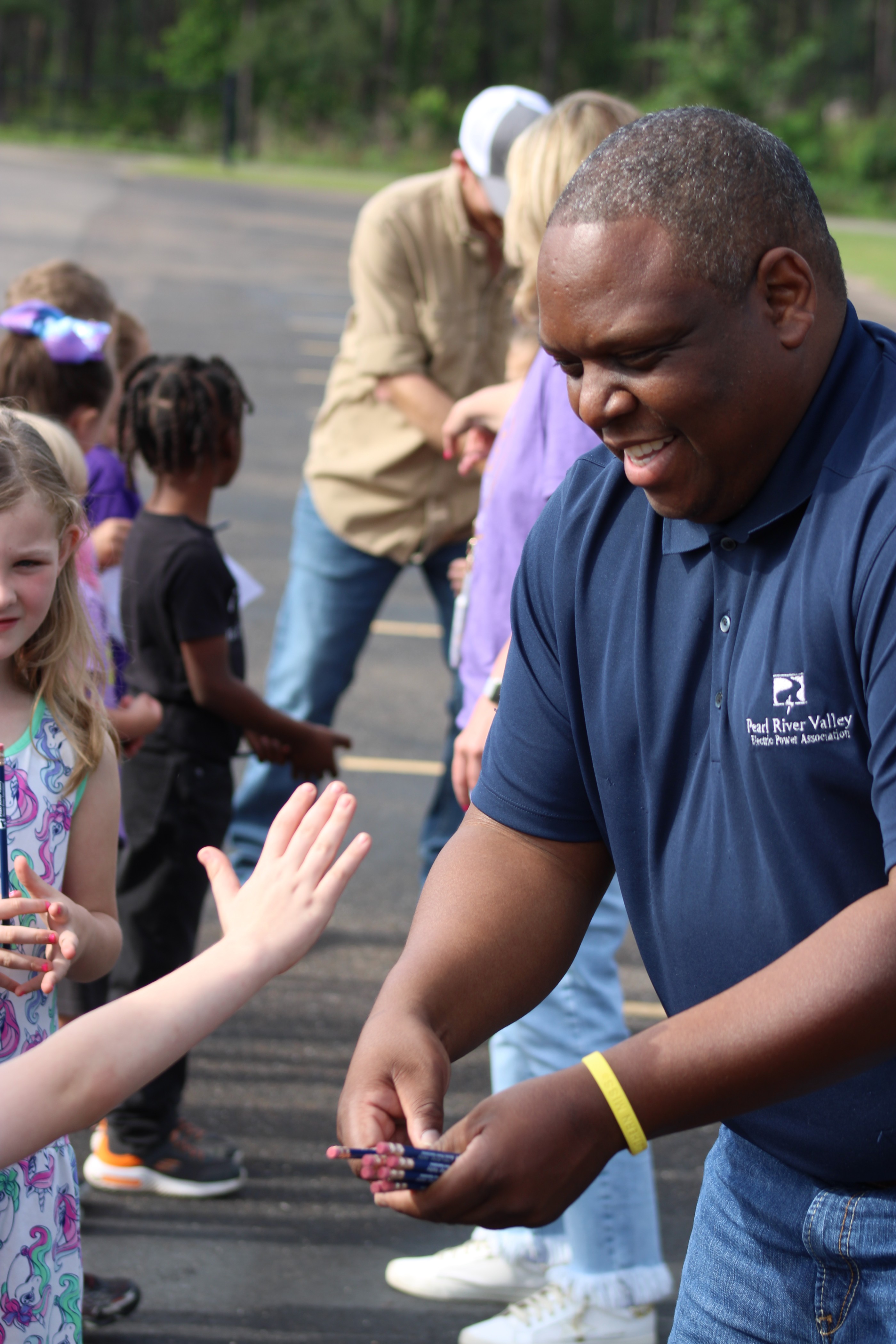 Pearl River Valley man passing out pencils to grade school kids